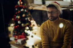 Young pensive man feeling lonely while spending New Year's eve alone at home.